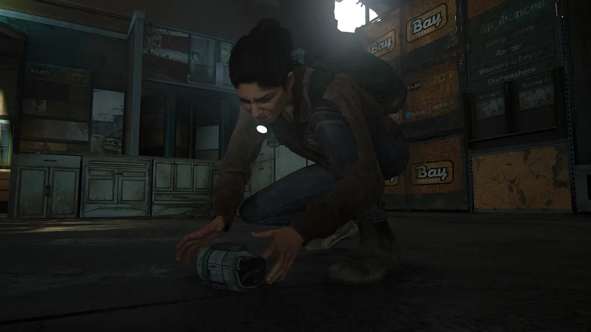 Dina crouching and placing a trap mine on the floor of a warehouse.